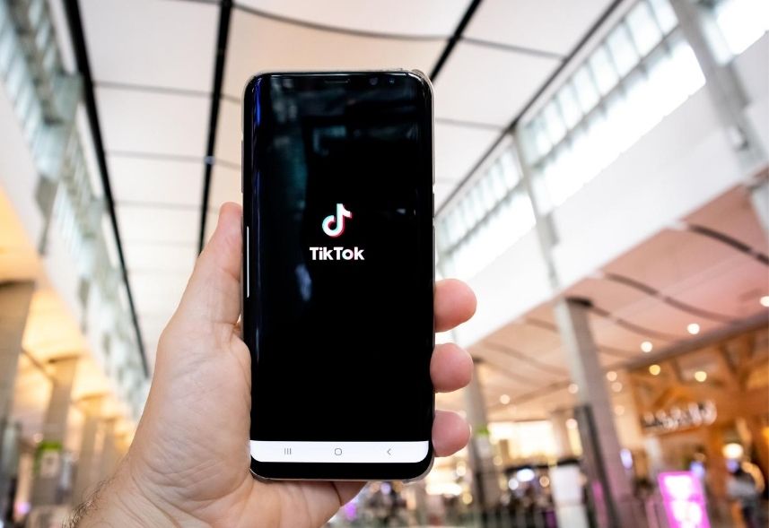 Ganhar dinheiro com TikTok: imagem de uma mão segurando um celular com o logo do TikTok na tela no aparelho