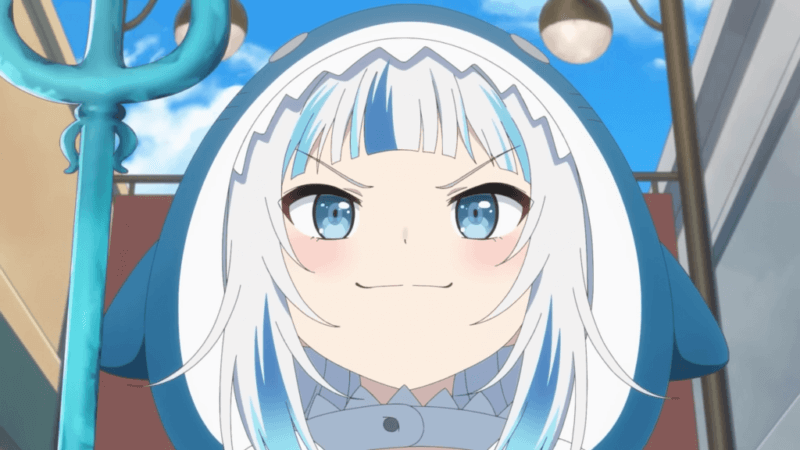 VTuber 12 VTuber Gawr Gura usando hoodie de tubarão azul e branco, segurando um tridente azul, com expressão confiante e bochechas coradas; céu e luminárias desfocadas ao fundo.