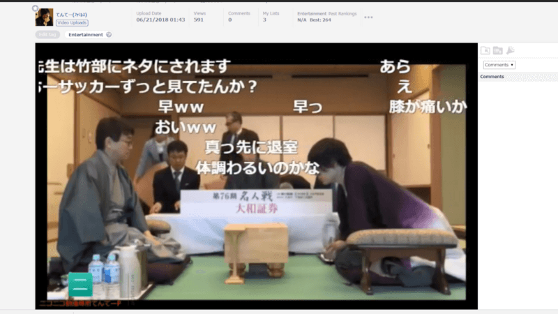 VTuber 9 Captura de tela de um vídeo hospedado no Niconico, mostrando uma partida de shogi em andamento em um ambiente tradicional japonês, com tatames e divisórias de madeira. Dois jogadores, vestidos com trajes formais japoneses, estão posicionados frente a frente com o tabuleiro de shogi entre eles. Há garrafas de água e uma garrafa térmica ao lado de um dos jogadores. Sobre a imagem, comentários em japonês aparecem sobrepostos na tela, característicos do estilo de exibição do Niconico.